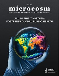 A gloved hand holds a Petri dish containing a multi-colored map of the world.